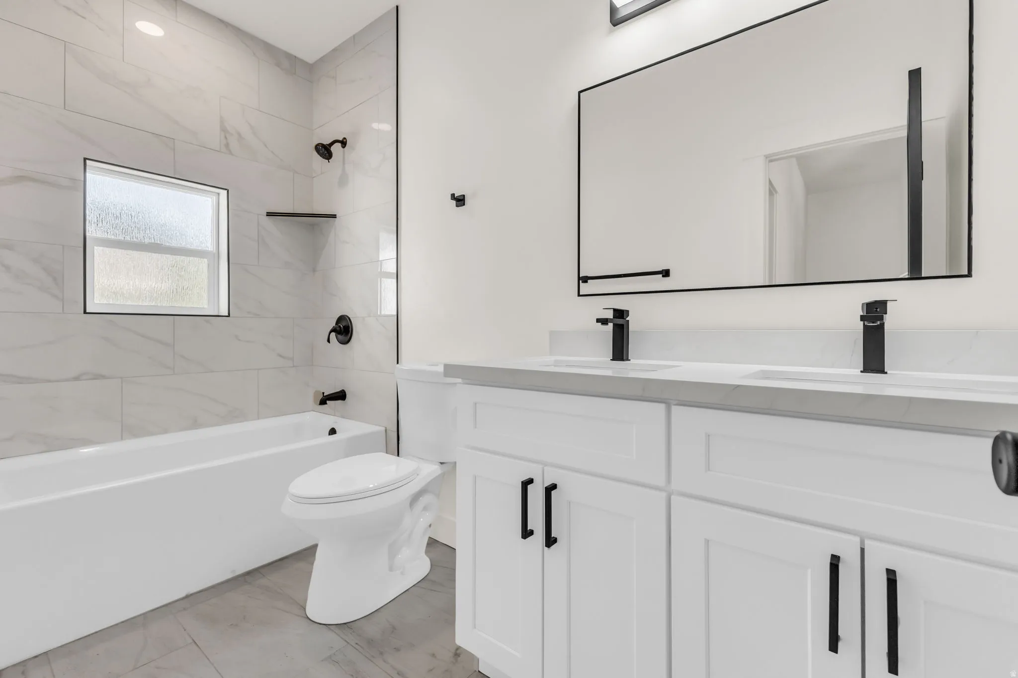 Modern bathroom featuring a dual vanity with white shaker-style cabinetry, matte black fixtures, and a large framed mirror