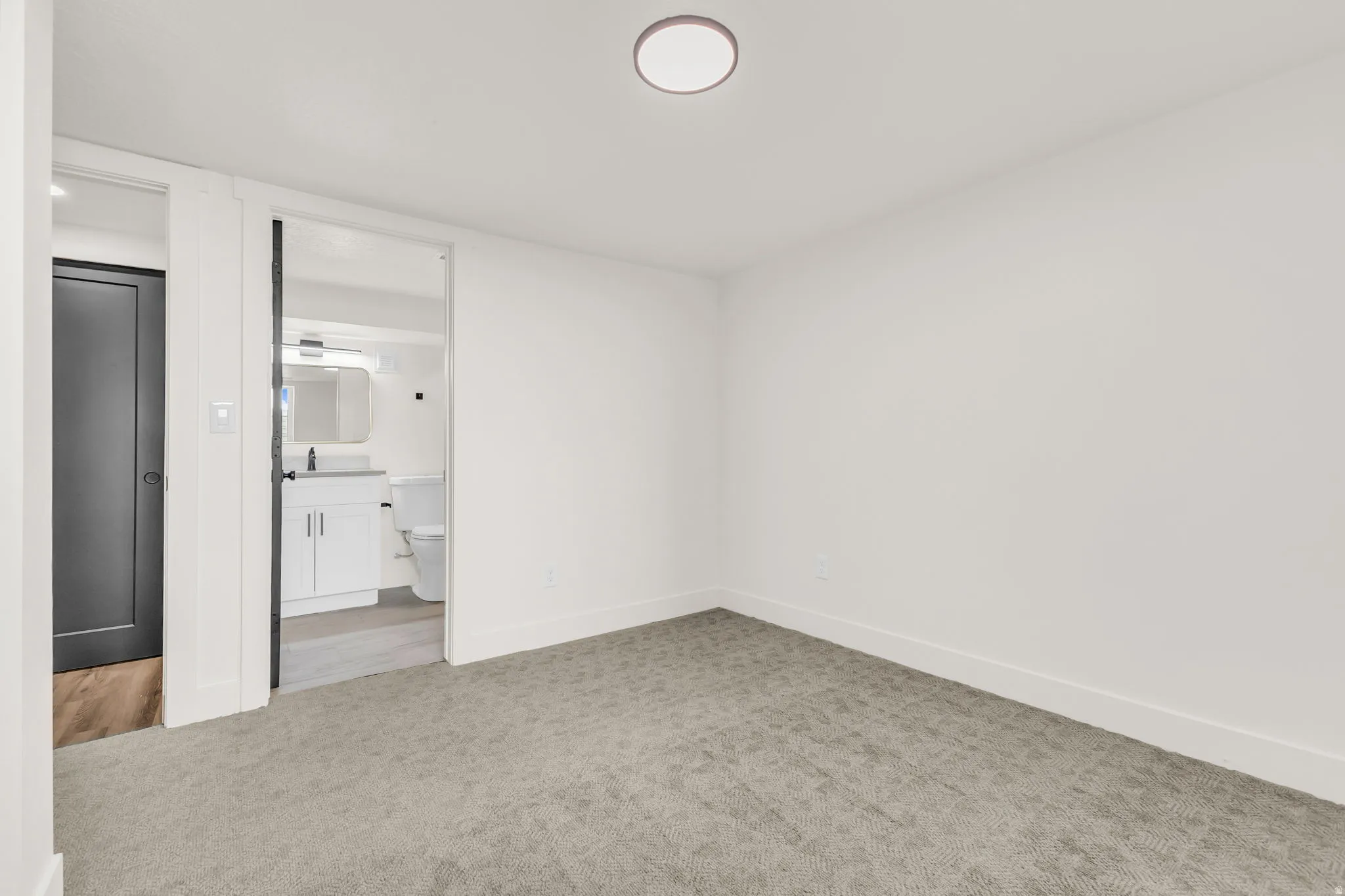 Carpeted room featuring a ceiling-mounted light fixture and white baseboards