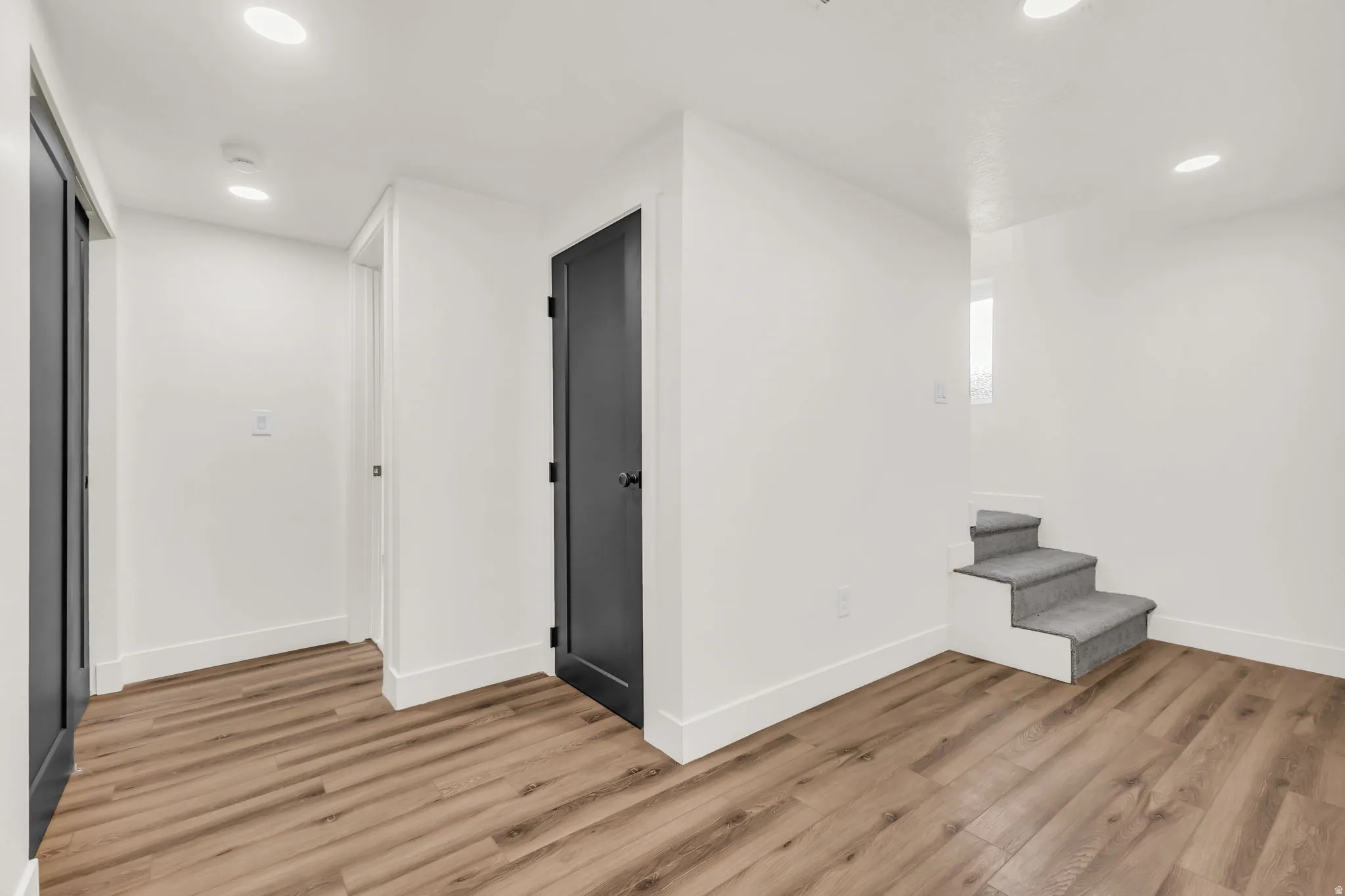 Open concept area with wood-finish flooring, recessed lighting, and white baseboards