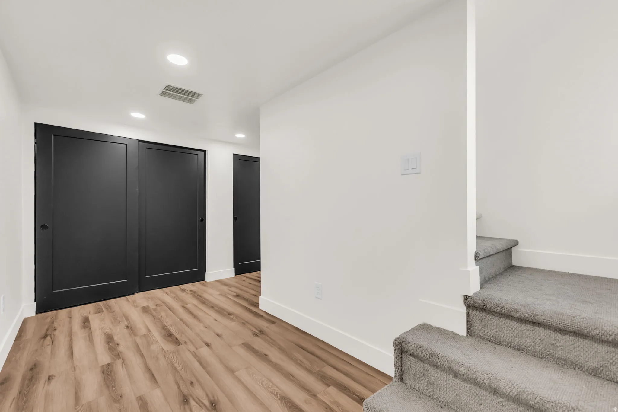 Hallway featuring wood-finish flooring, recessed lighting, and white baseboards