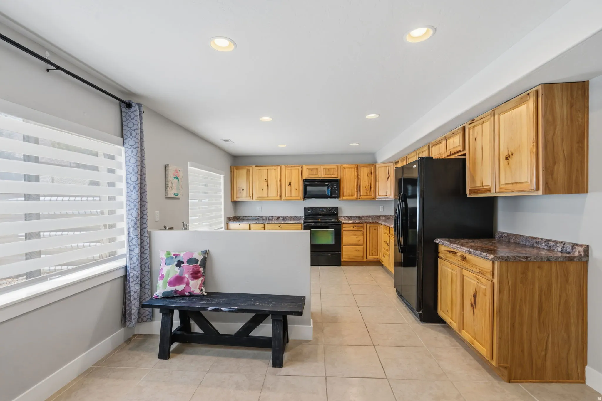 Easy access to add an entrance to bsement. Kitchen featuring wood-finish cabinetry, black appliances, and stone-look countertops