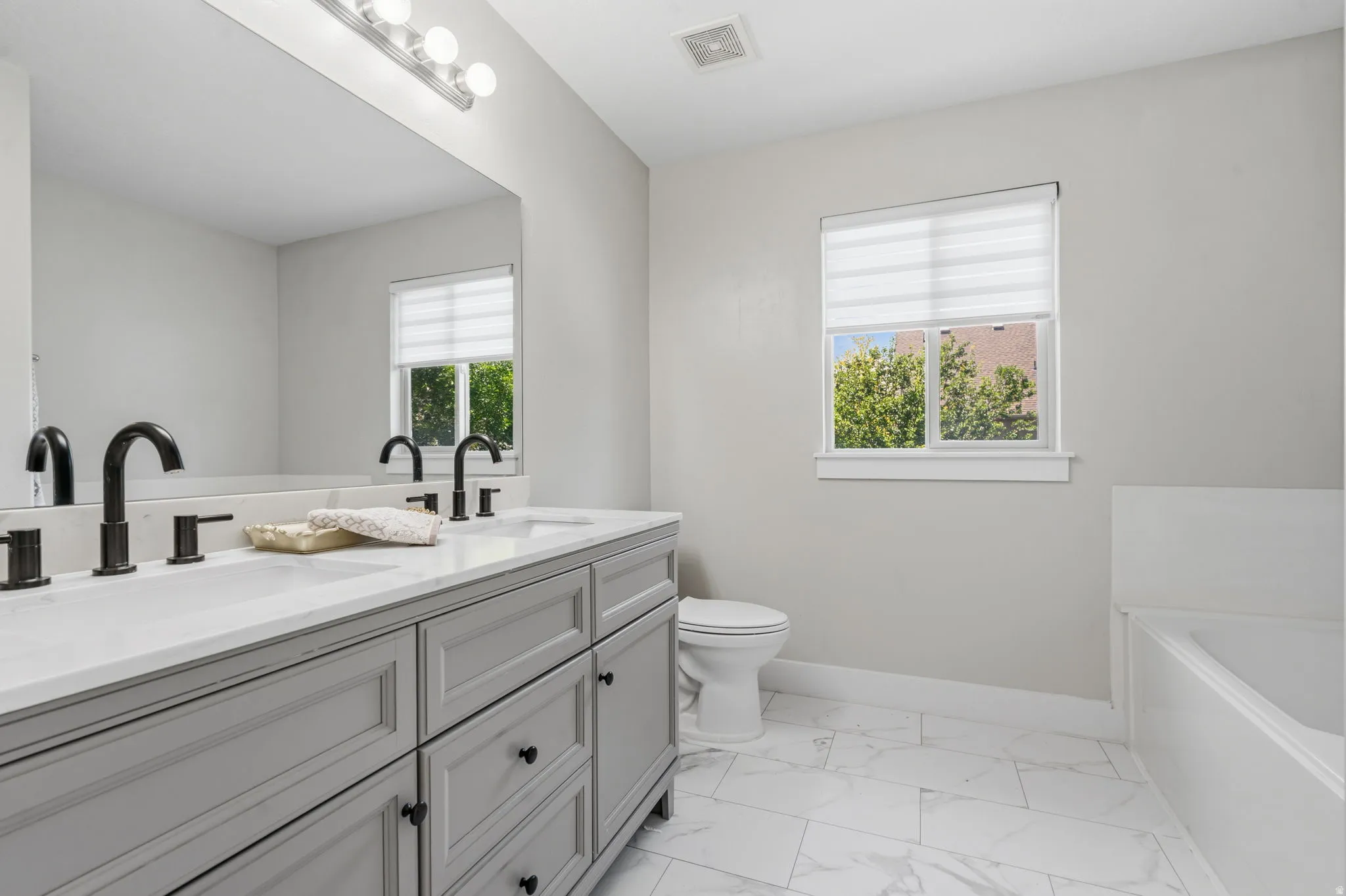 Dual vanity featuring a white countertop with integrated sinks and matte black fixtures