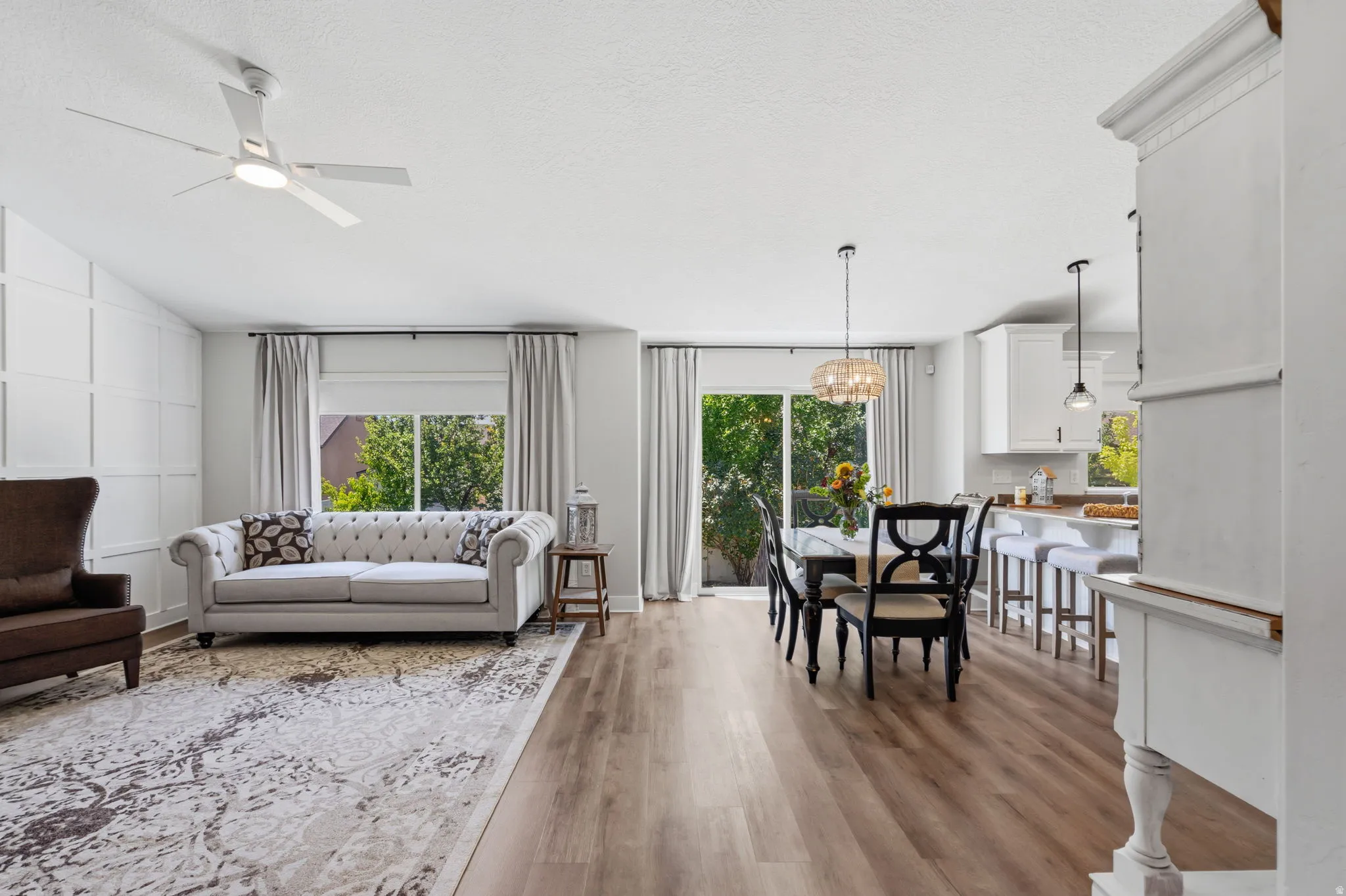 Open-concept living space featuring wood-finish flooring, a contemporary ceiling fan, and a grid accent wall