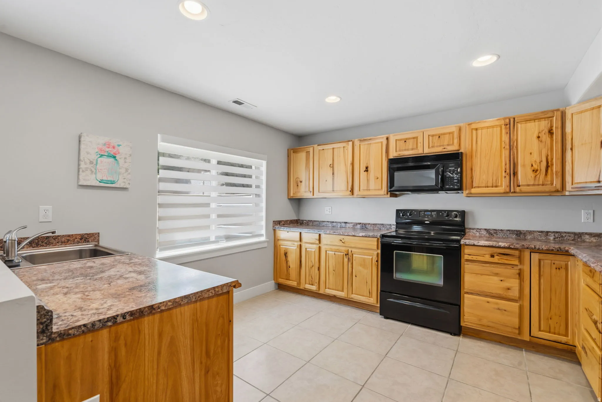 Kitchen featuring wood cabinetry, laminate countertops, a black electric range, a black microwave, and recessed lighting