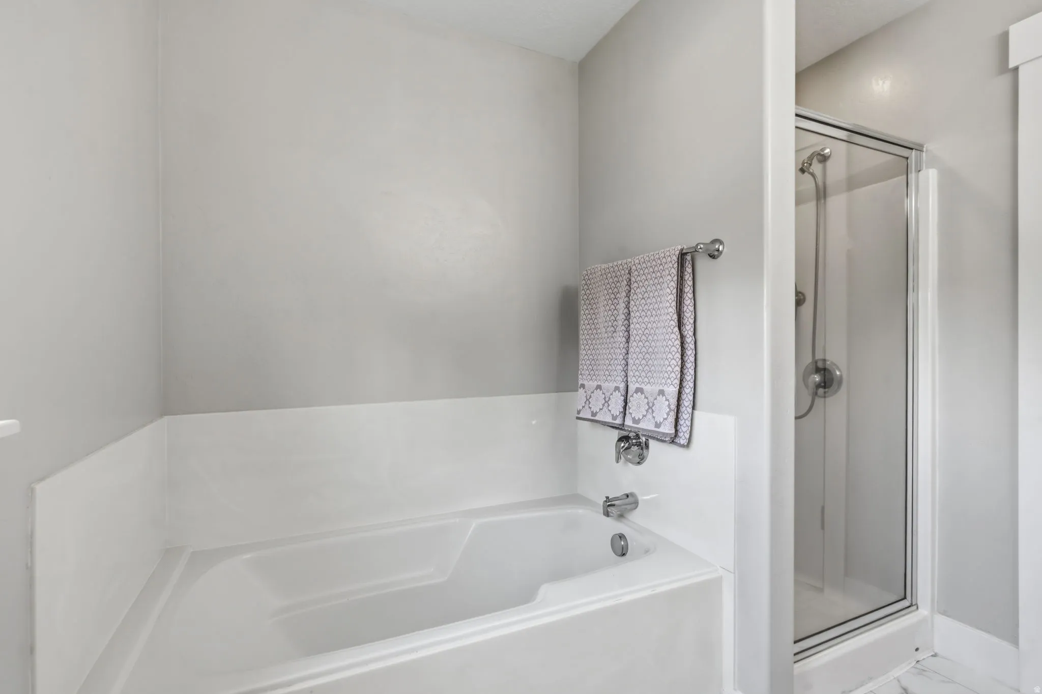 Bathroom featuring a built-in tub with chrome fixtures and a separate glass-enclosed shower