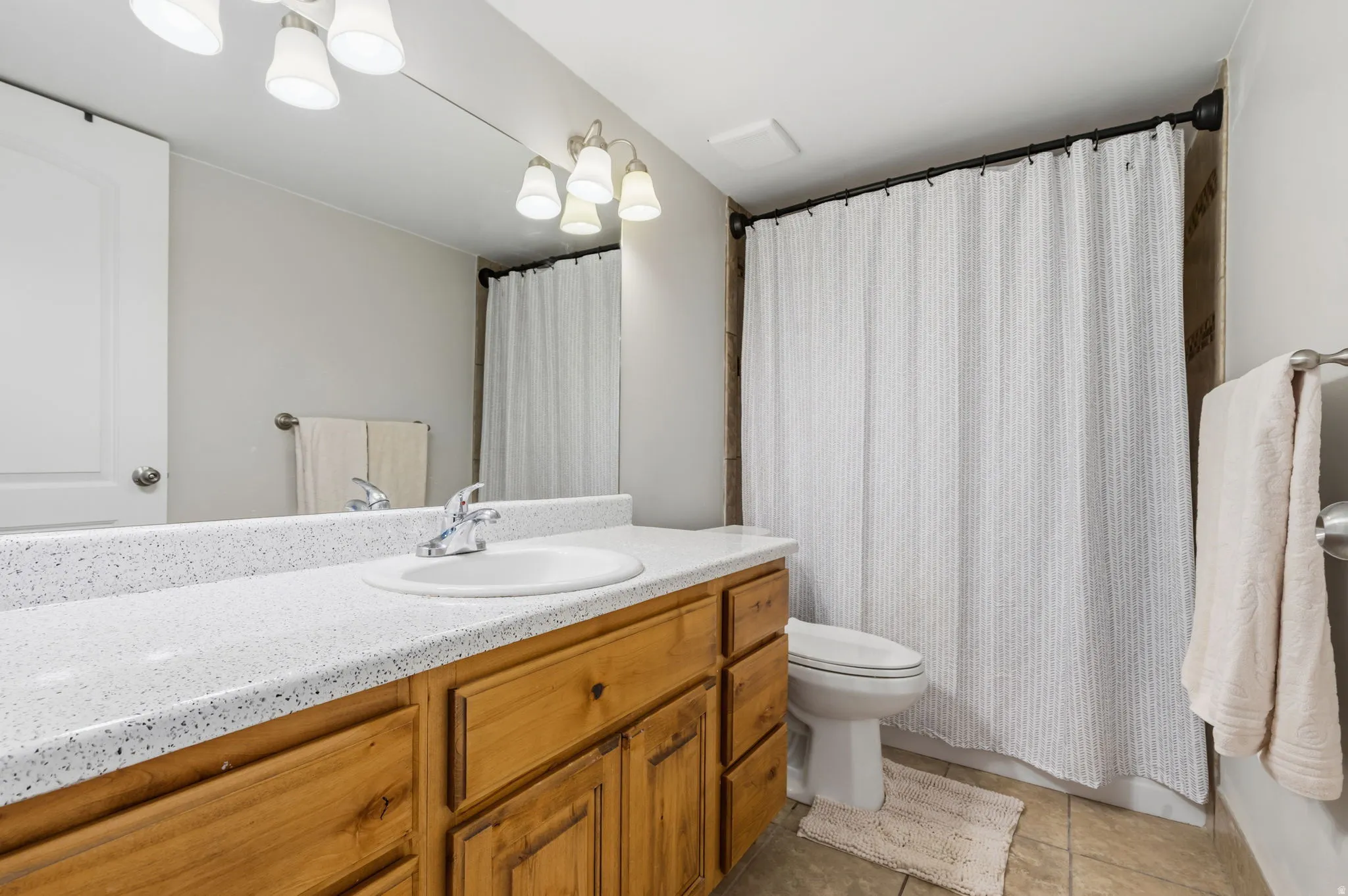 Bathroom featuring a single vanity with wood cabinetry, a white countertop, and an integrated sink