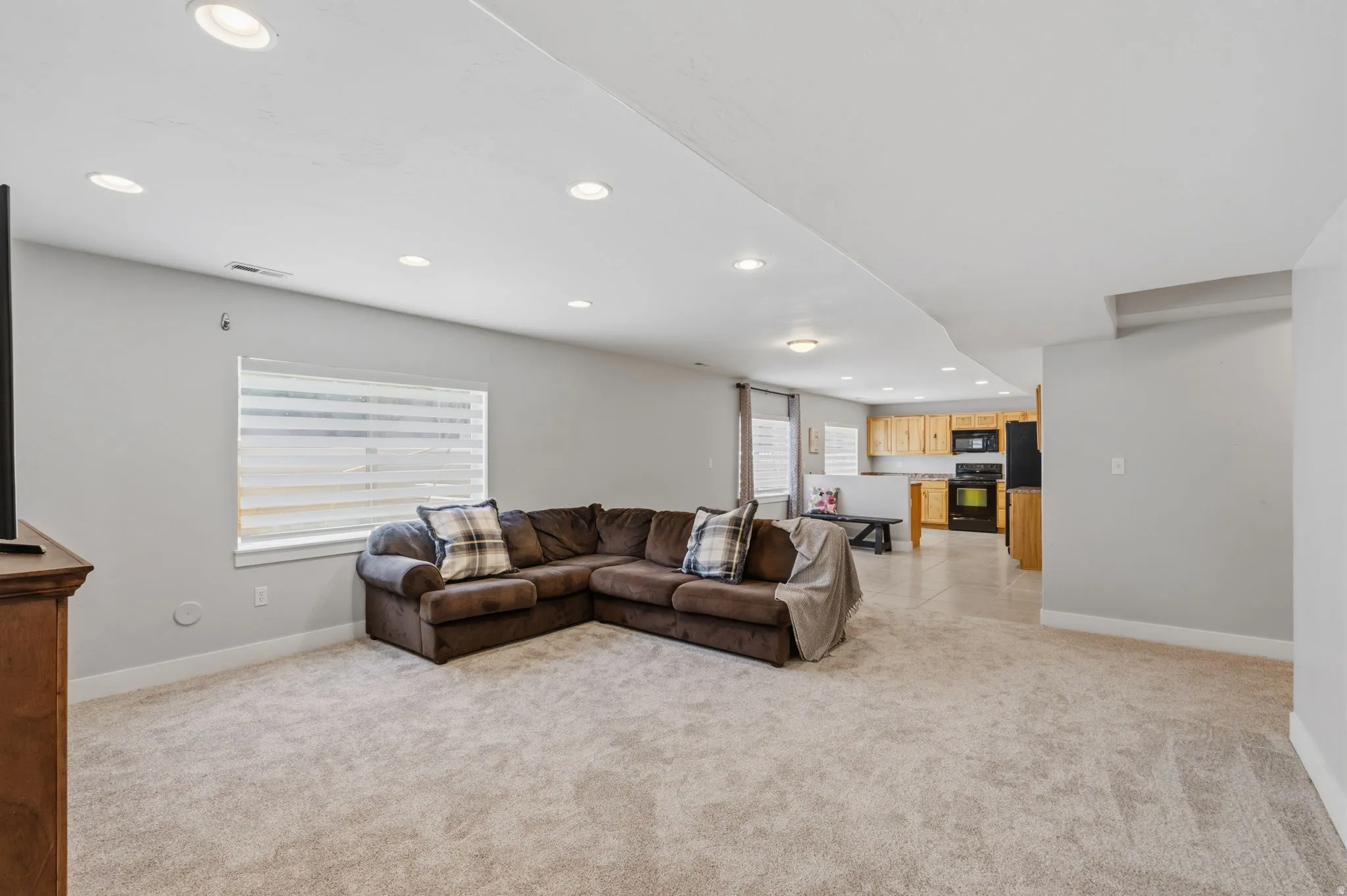 Carpeted living area with recessed lighting, light gray wall paint, and a window with horizontal blinds