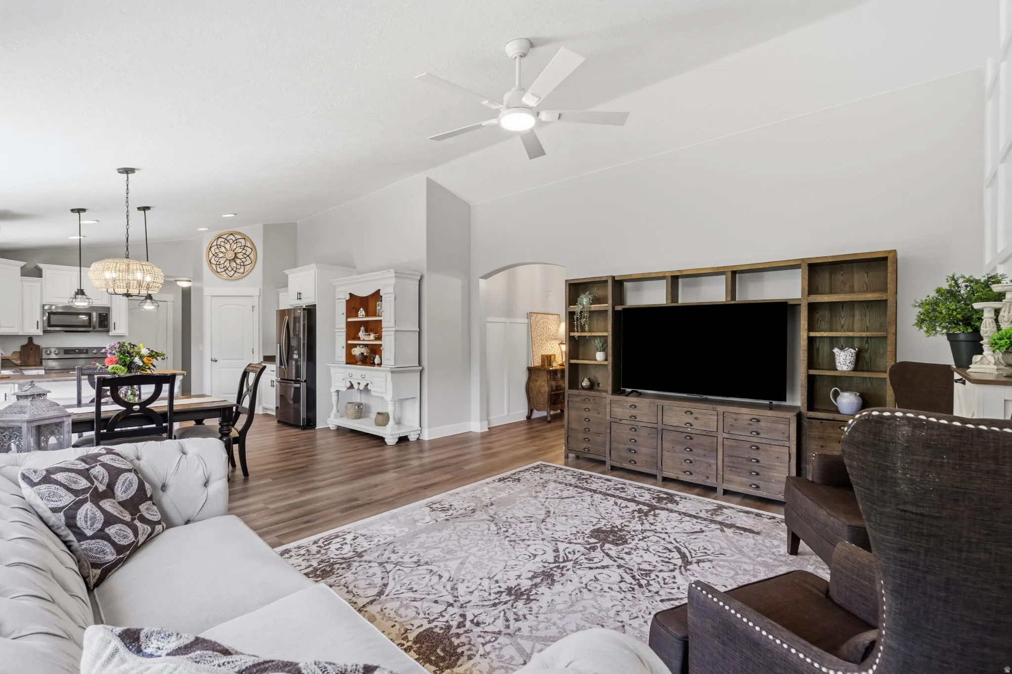 Open-concept living area featuring wood-finish flooring, vaulted ceilings, and a ceiling fan
