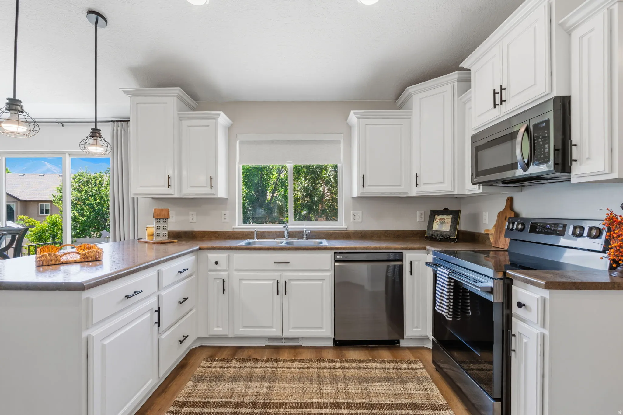 Kitchen featuring white cabinetry with dark hardware, a stainless steel dishwasher, an over-the-range microwave, and a black electric range