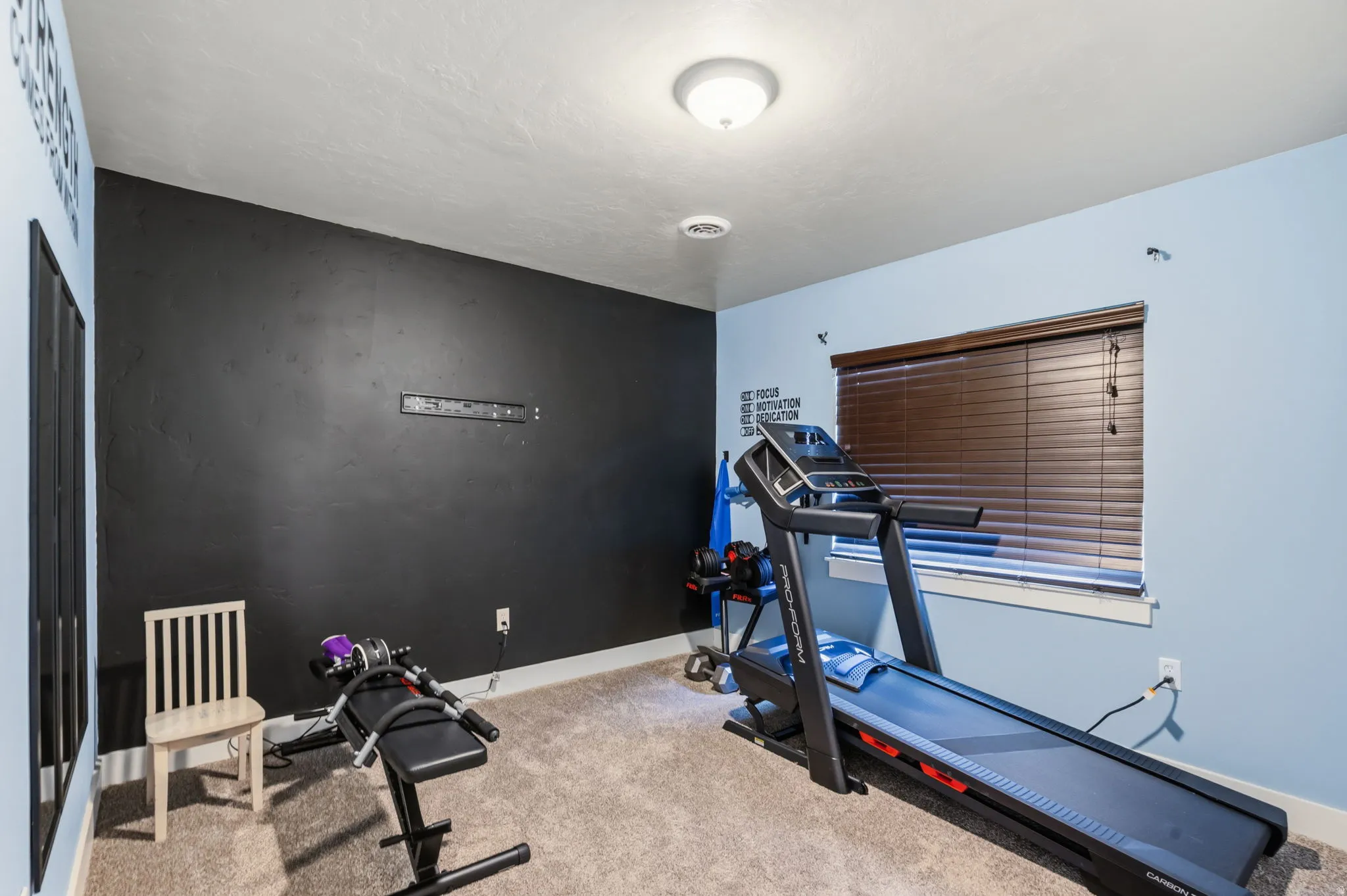 Carpeted room featuring a window with wood-finish blinds, a flush mount ceiling light, and a two-tone wall treatment