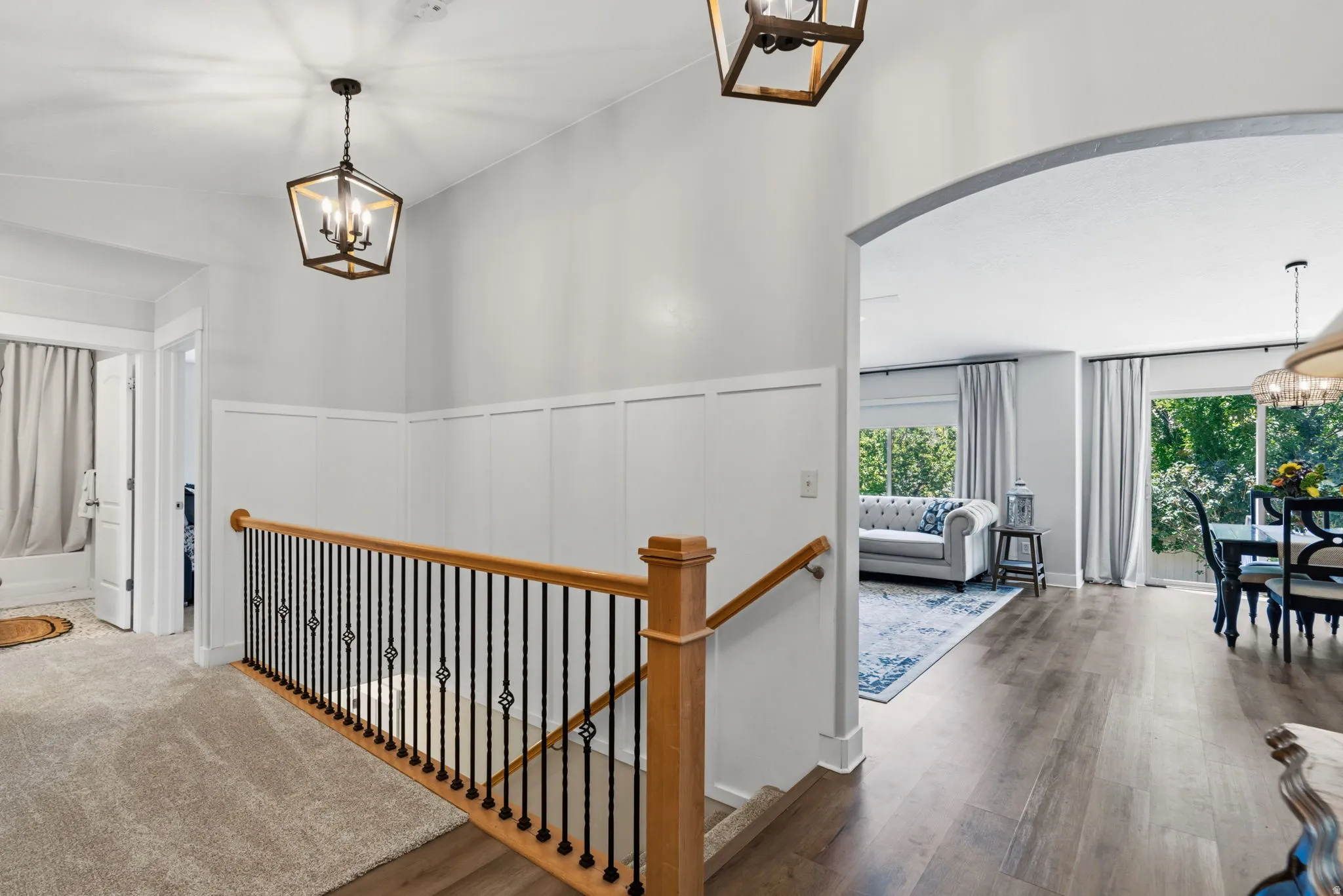 Upper landing featuring board and batten wall paneling, two contemporary pendant light fixtures, and carpeted flooring