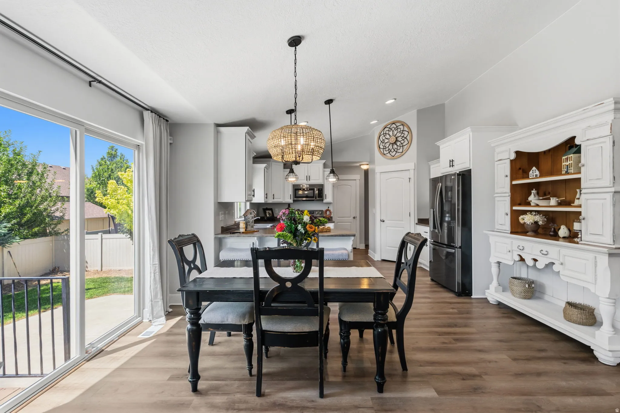 Dining area featuring wood-finish flooring, a contemporary chandelier, and direct patio access through sliding glass doors