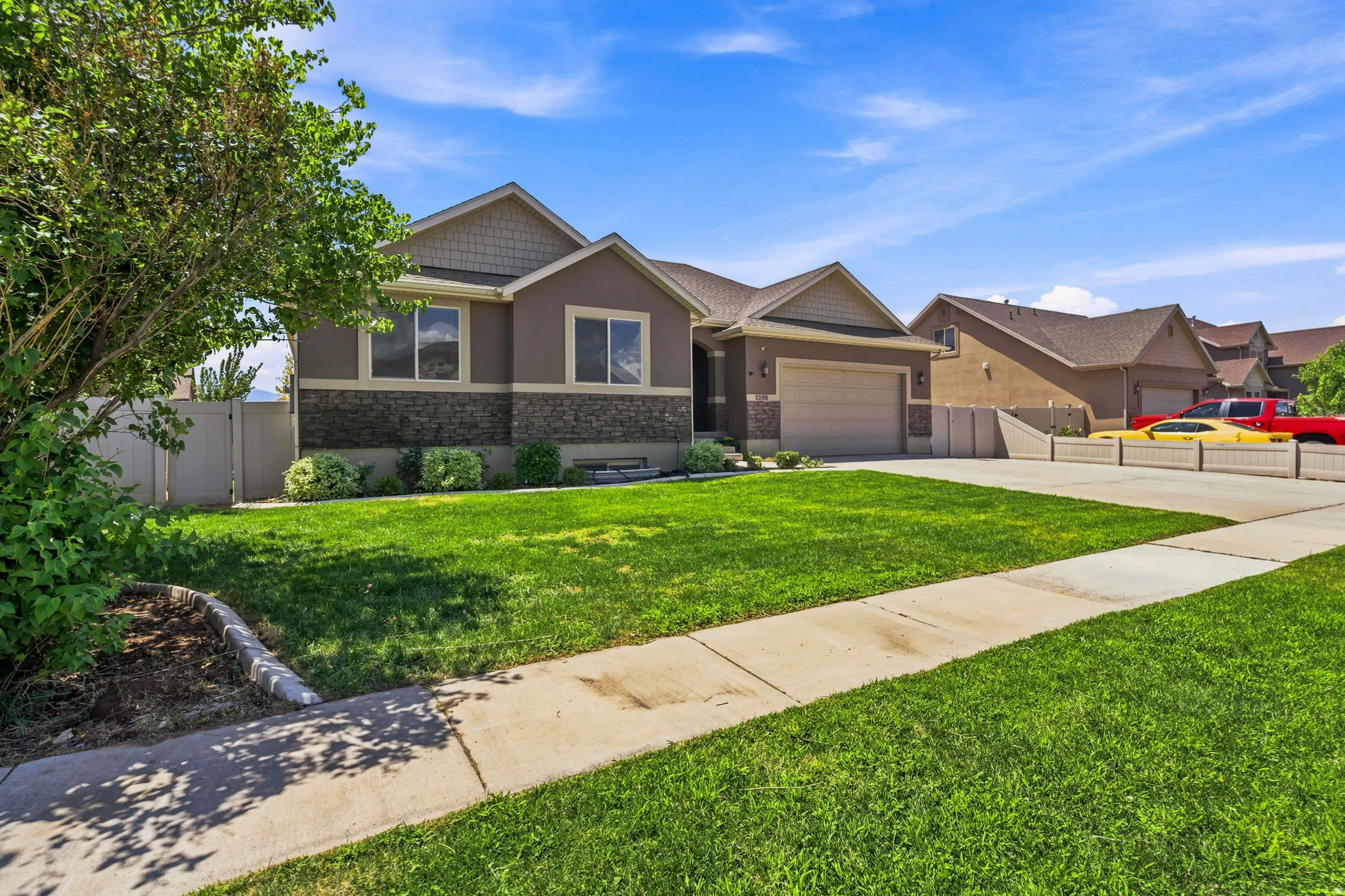 Single-story residence featuring a two-car garage, stone and stucco exterior, and a manicured front lawn