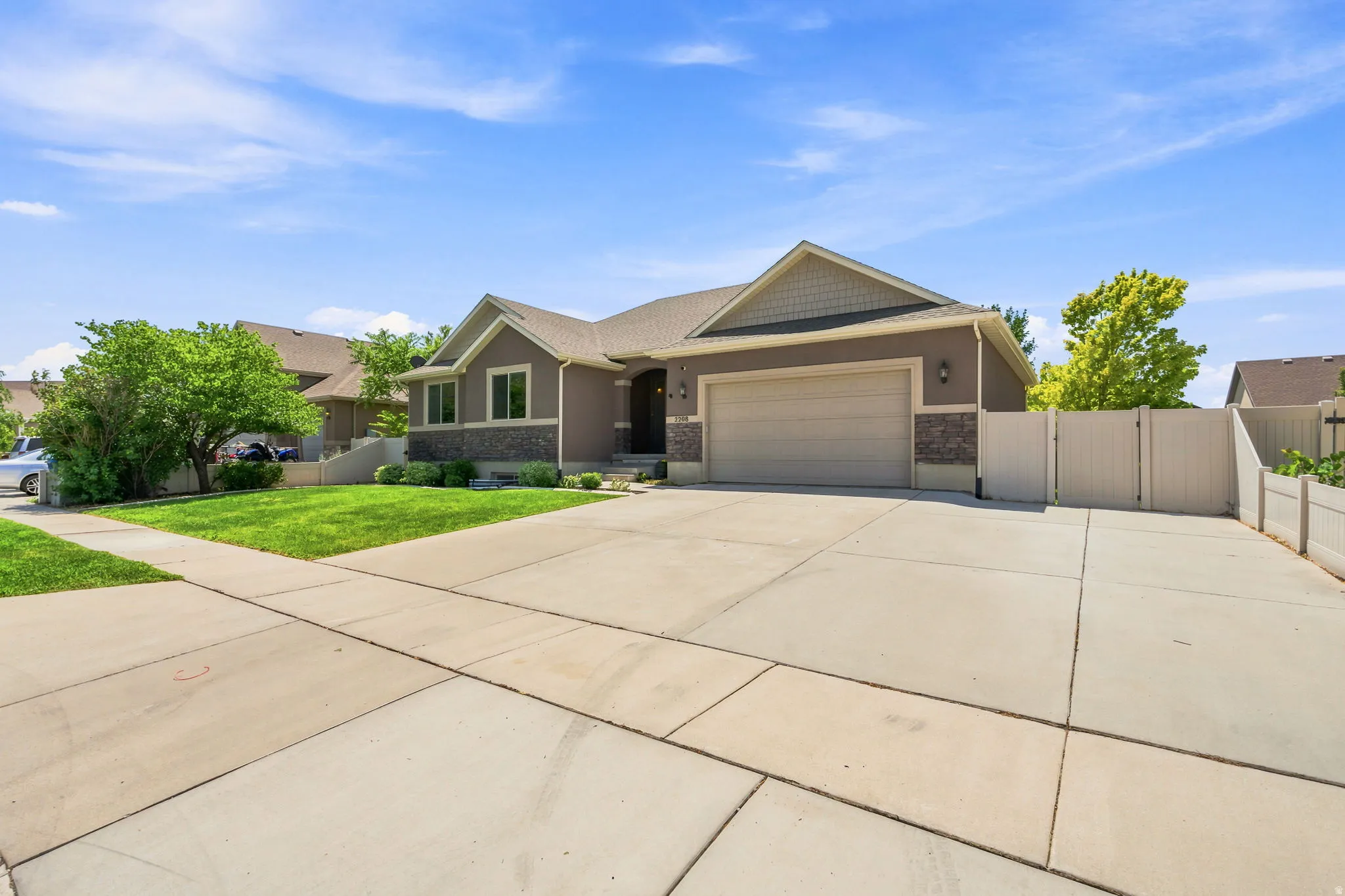 Contemporary ranch-style residence featuring a two-car garage, concrete driveway, and a white privacy fence