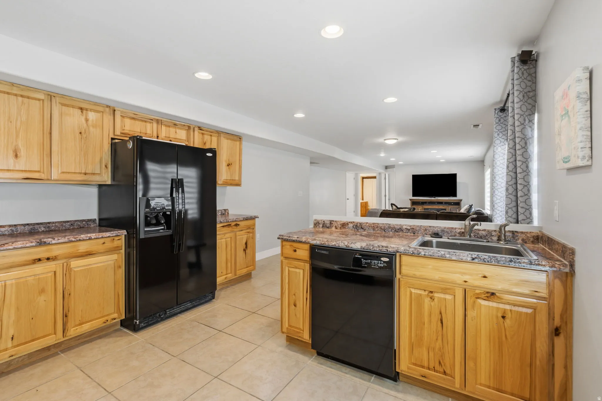 Kitchen featuring light wood cabinetry, stone-look countertops, and tile flooring