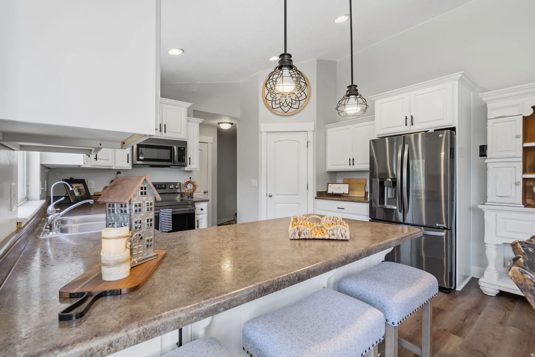 Kitchen featuring a large central island, white cabinetry, stainless steel appliances, and pendant lighting