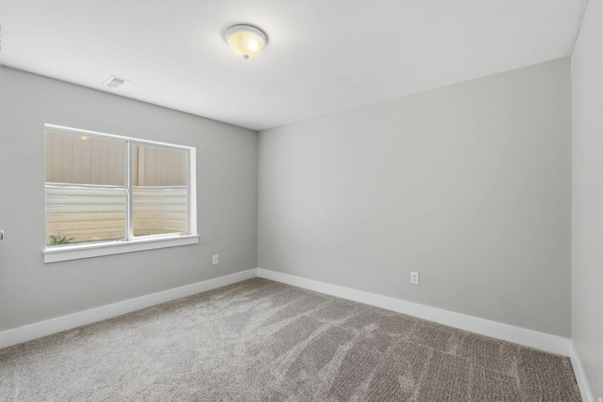 Room with light gray wall paint, gray patterned carpeting, and white baseboards