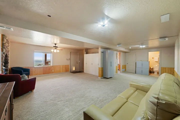Spacious room with plush carpet flooring, a stone-clad architectural feature, and wood paneling along the lower walls