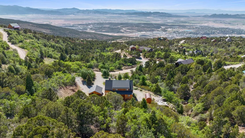 Terraced property featuring a cabin-style residence with a dark roof, surrounded by extensive natural landscaping