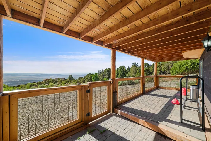 Expansive covered patio featuring a wood beam ceiling, natural wood posts, and a stone paver floor