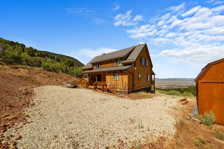 Wood-sided log cabin structure featuring a metal roof and multiple windows