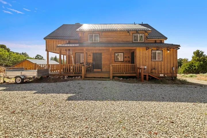 Log cabin-style residence featuring a metal roof, an elevated front porch with wood railings, and multiple windows