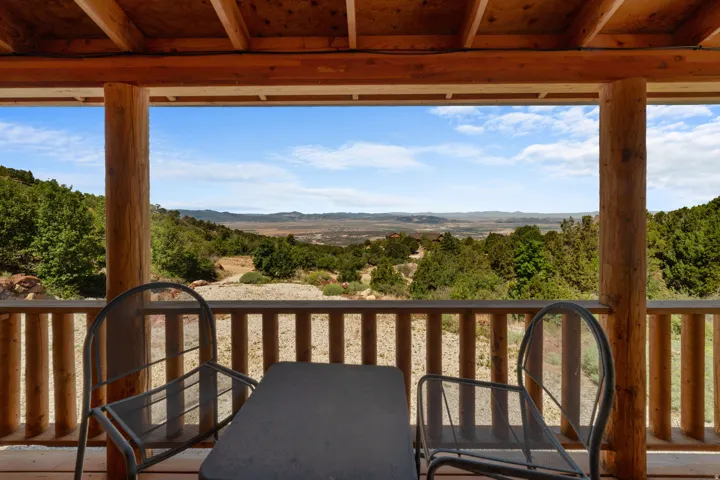 Expansive covered deck featuring natural wood-finish posts and railing, with a clear sightline to distant hills and a broad sky