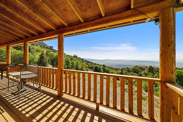 Expansive covered porch featuring a natural wood ceiling, log-style support beams, and a wood-slat railing