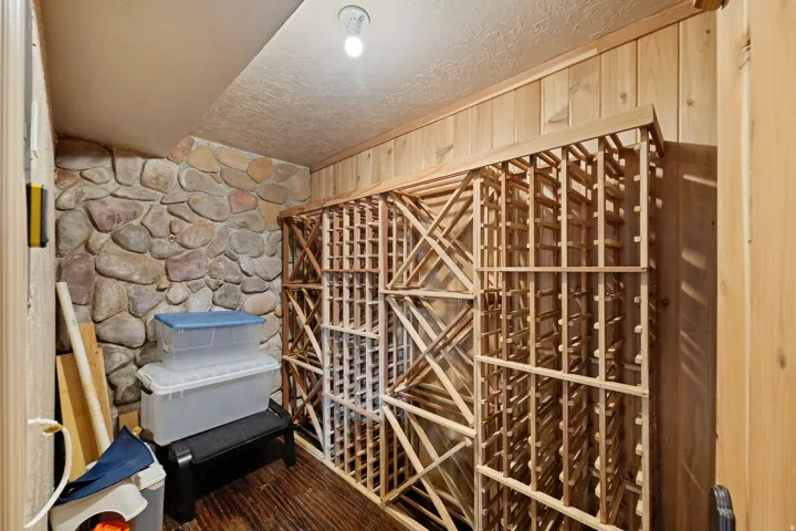 Storage room featuring stone accent wall, wood-finish flooring, wood plank paneling, and built-in wood wine racks