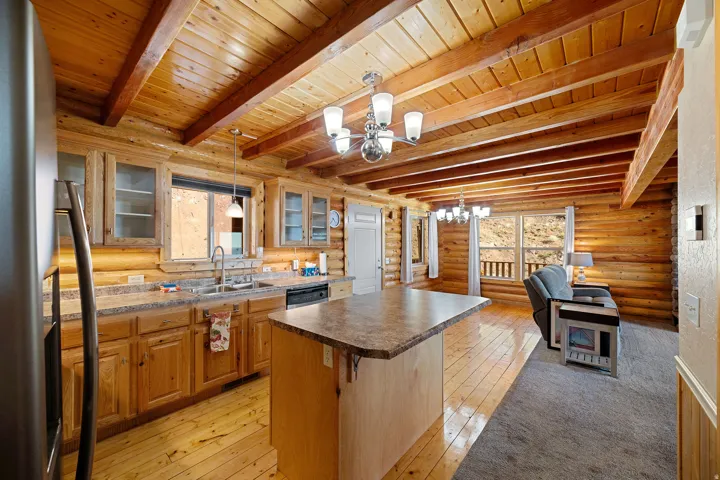 Open-concept kitchen and living area featuring exposed wood beam ceilings and wood-finish flooring