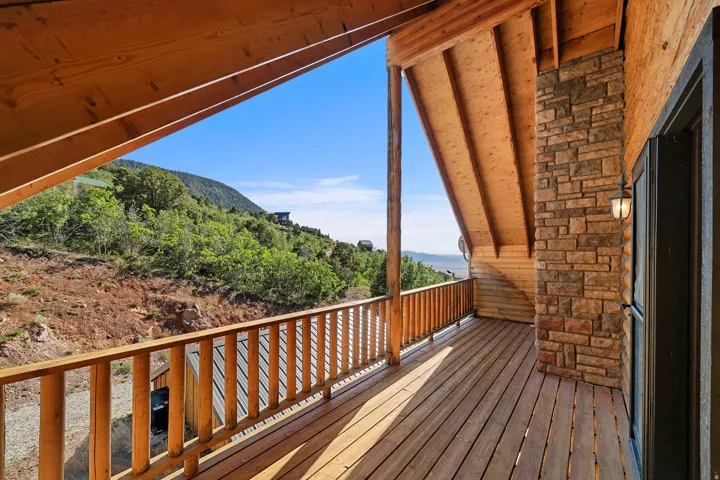 Expansive wood deck with a natural wood railing, featuring a stone-clad exterior wall and a prominent wood-plank ceiling