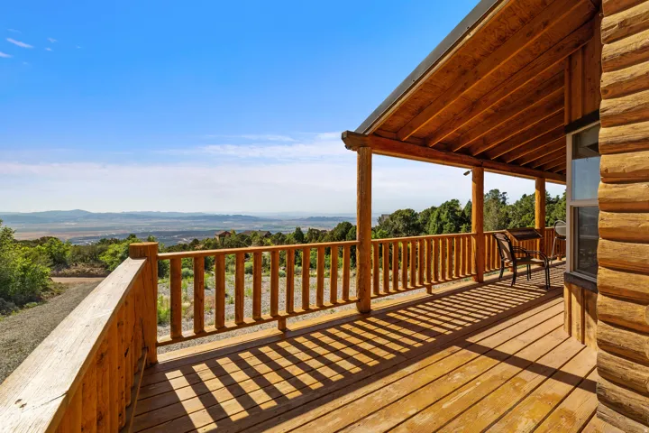 Expansive wood-finish deck with a rustic railing and overhead covering