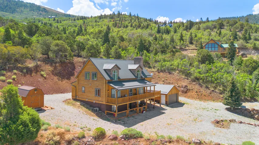 Log-sided residence featuring a metal roof, stone chimney, and a multi-level deck