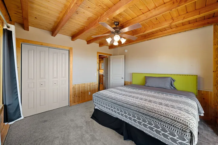 Bedroom featuring a wood-finish tongue and groove ceiling, exposed wood beams, and a ceiling fan with integrated lighting