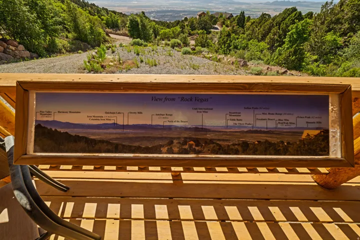 Expansive wooden deck featuring an interpretive display, a natural wood railing, and a panoramic mountain landscape