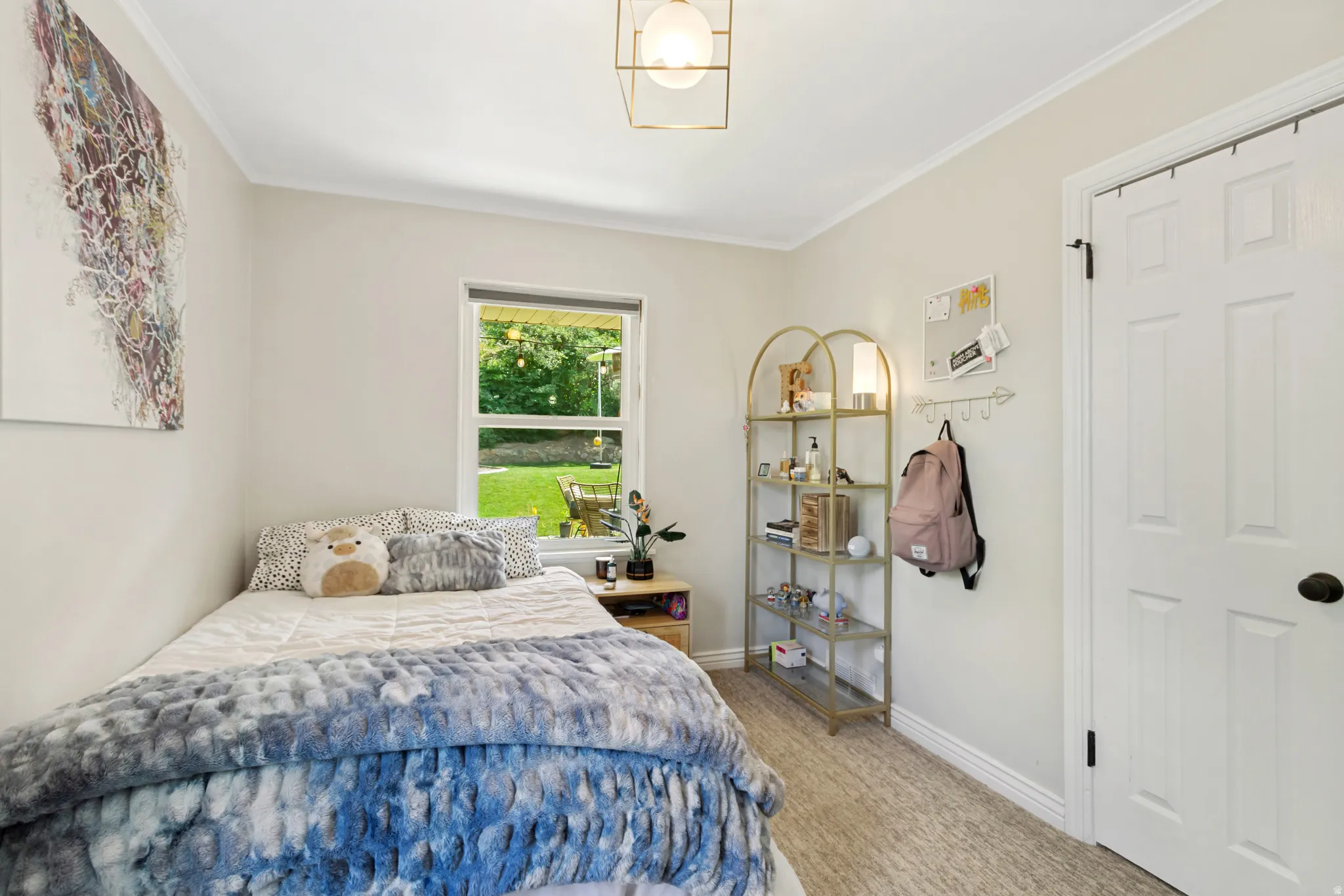 Light-filled room featuring a double-hung window with exterior views, crown molding, and neutral wall tones