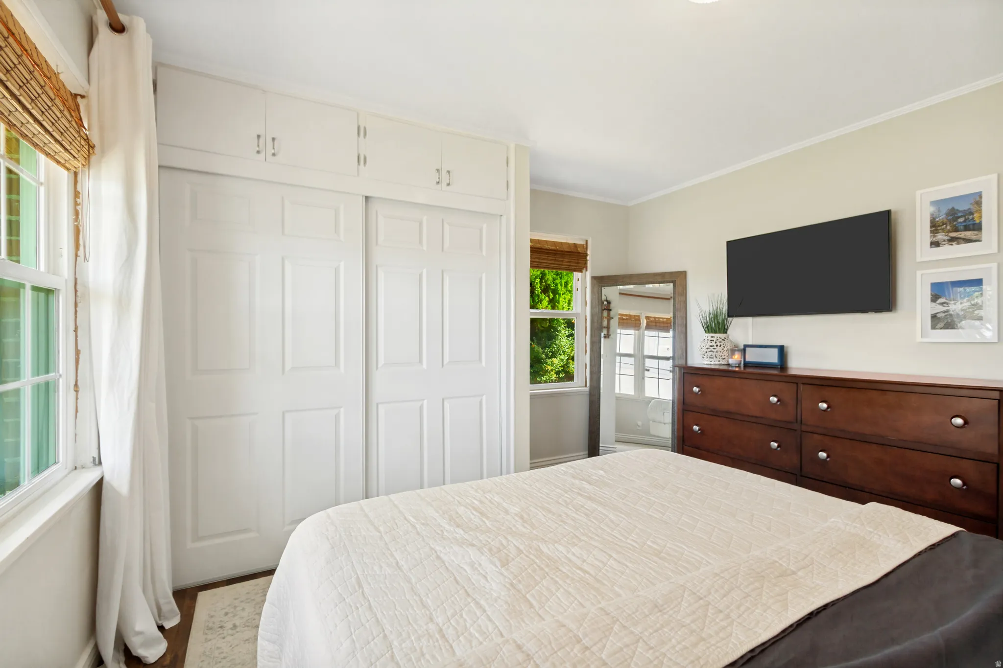 Window with natural light, integrated overhead storage, two-panel closet doors, wood-finish flooring, and recessed lighting
