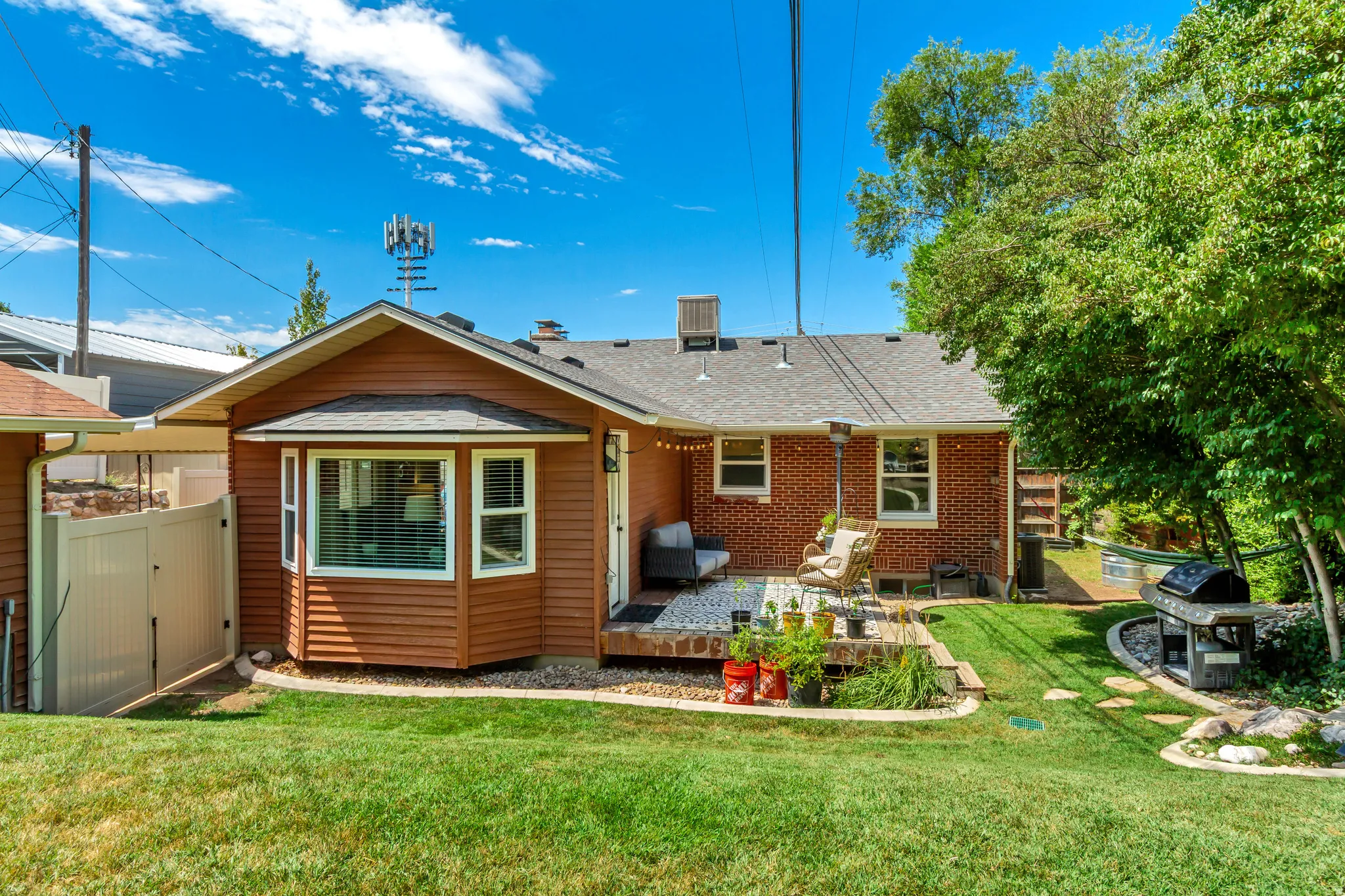 Expansive backyard featuring a manicured lawn, a red brick exterior, and a wood-finish deck