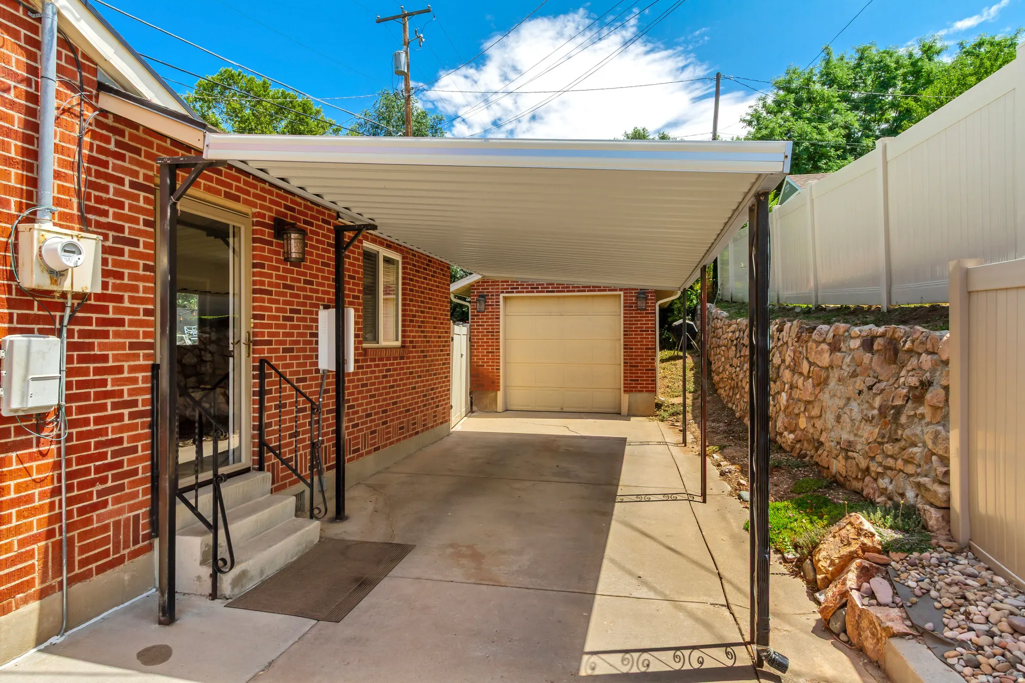Brick exterior featuring a covered carport, concrete driveway, and garage