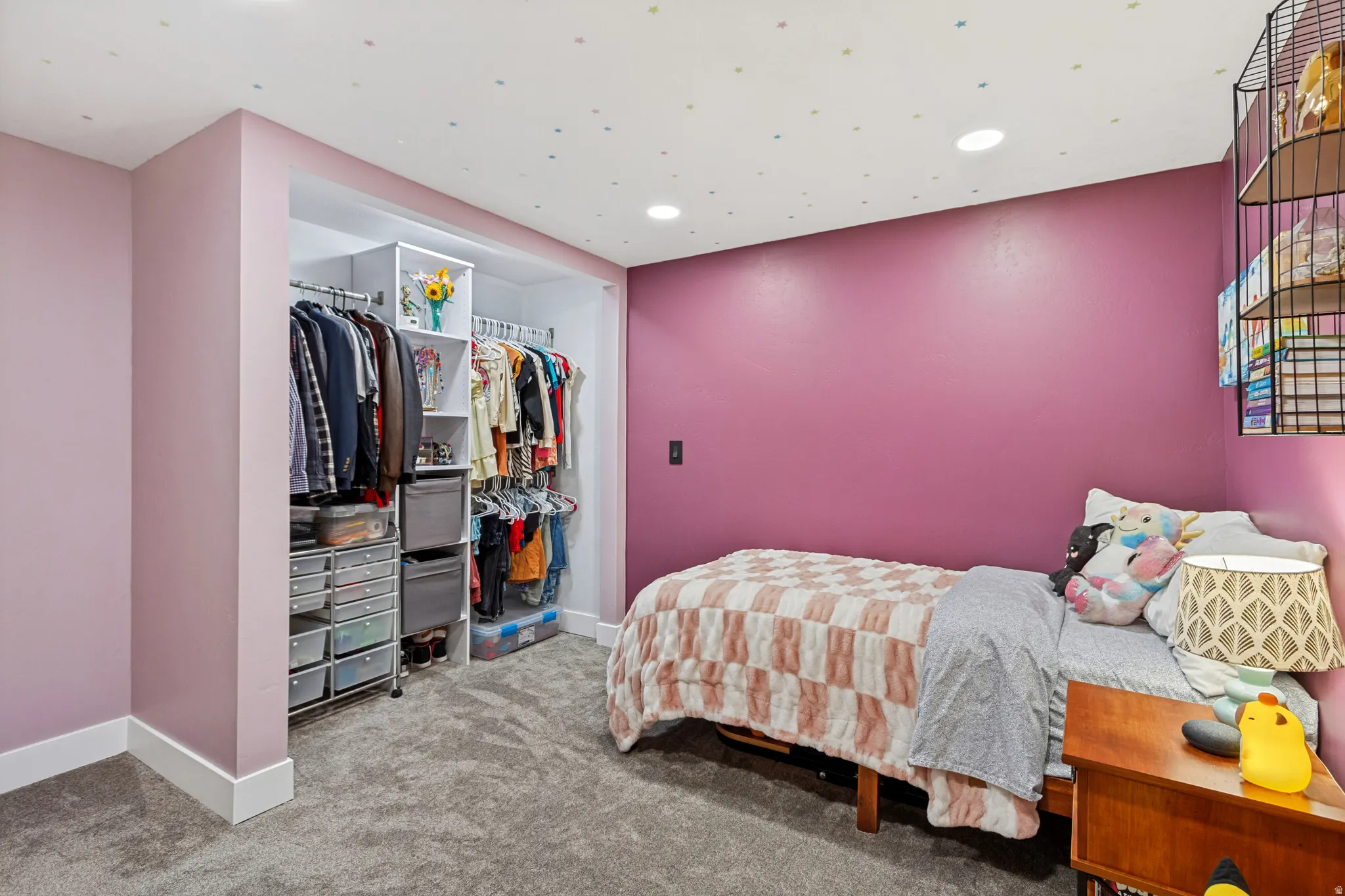 Bedroom featuring a built-in closet system with hanging rods and shelving, recessed lighting, and soft carpet flooring