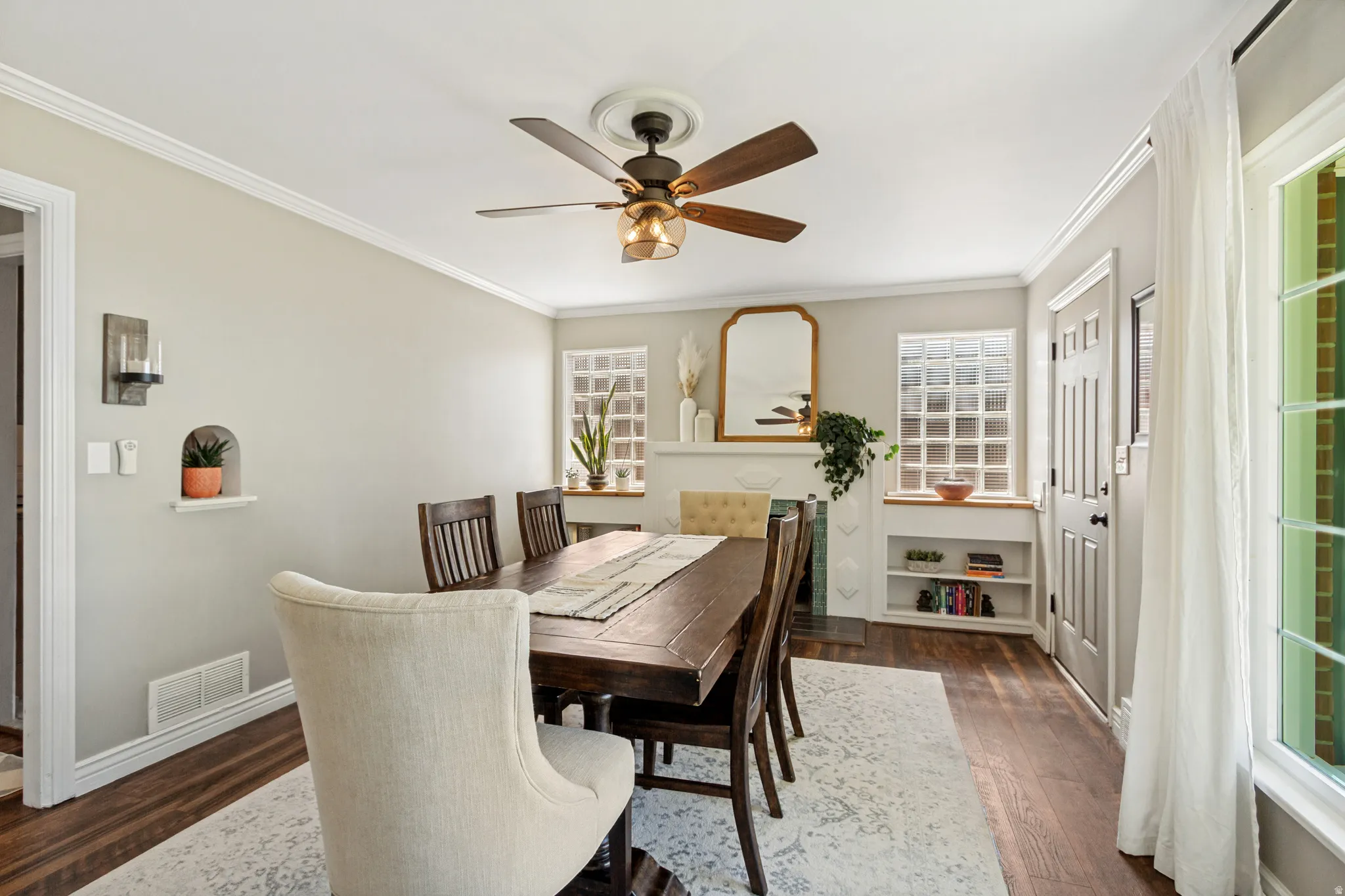 Dining area featuring wood-finish flooring, a ceiling fan with light fixture, decorative wall niche, and built-in shelving