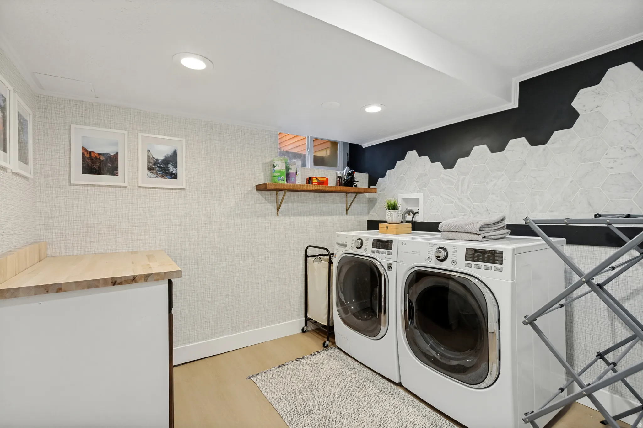 Dedicated laundry area featuring recessed lighting, light wood-finish flooring, and a countertop with wood-finish surface