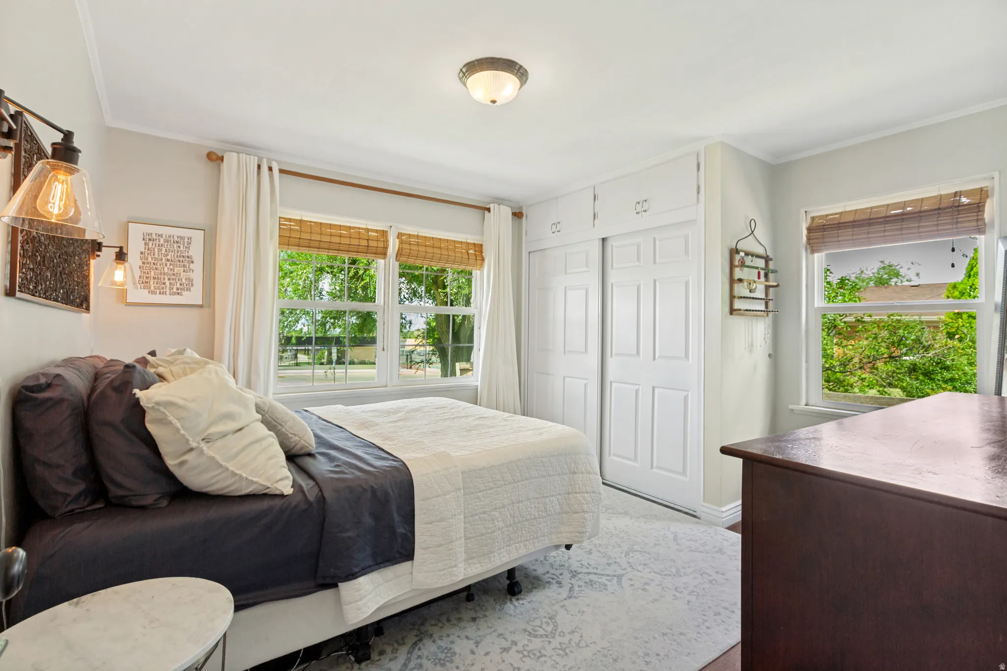 Recessed sliding closet doors with upper cabinetry, multiple windows, and a flush mount ceiling light