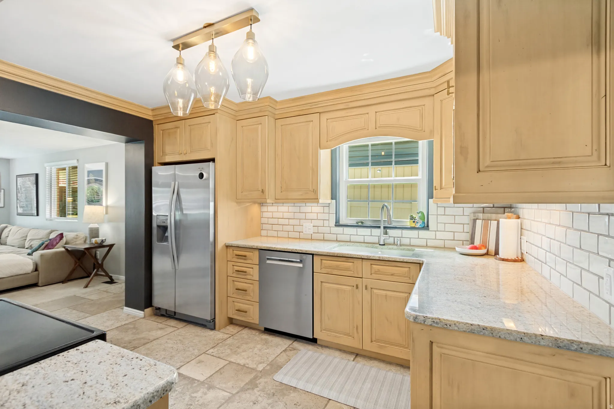 Kitchen featuring light wood-finish cabinetry, light-toned countertops, subway tile backsplash, and a window above the sink