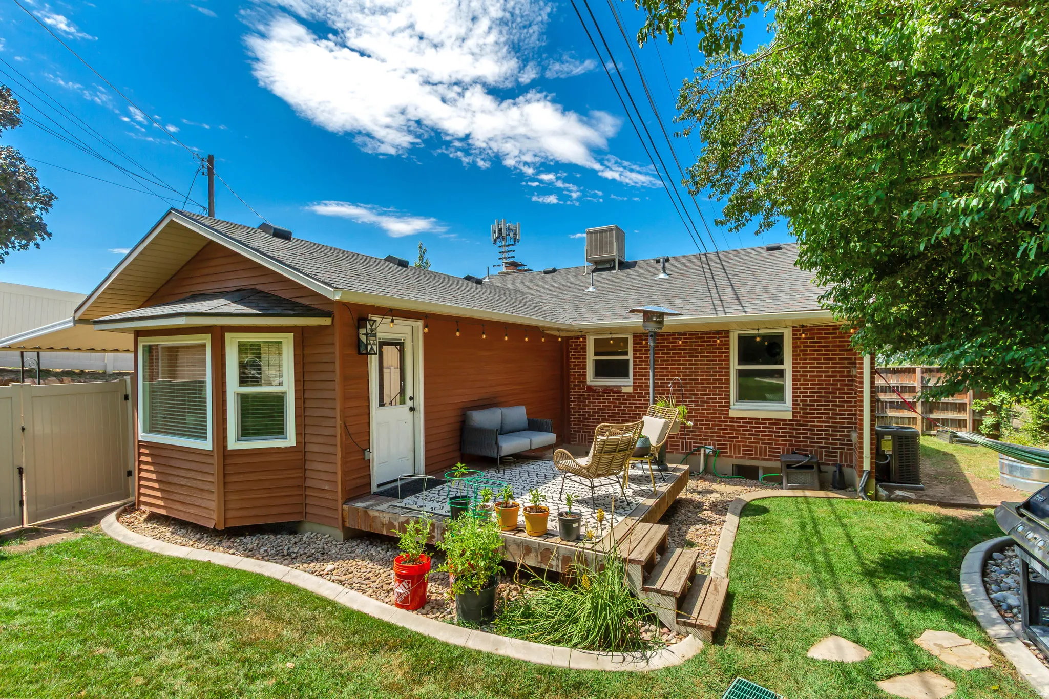 Backyard featuring a multi-level wooden deck with white gravel accents, a manicured lawn, and a red brick exterior