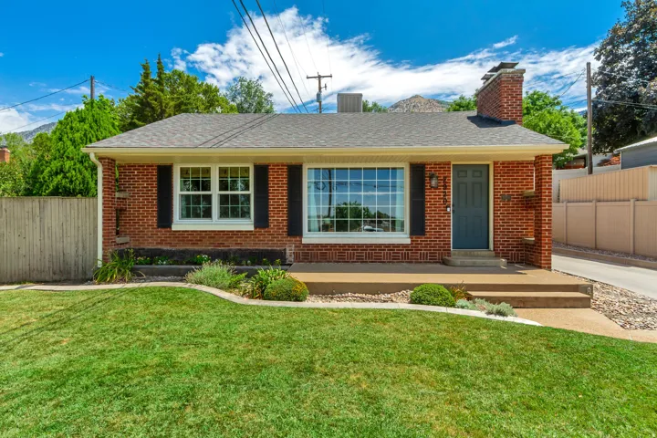 Brick exterior featuring a dark gray entry door and a coordinating chimney