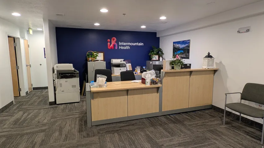Reception area featuring a wood-finish desk, patterned carpet flooring, recessed lighting, and a dark accent wall
