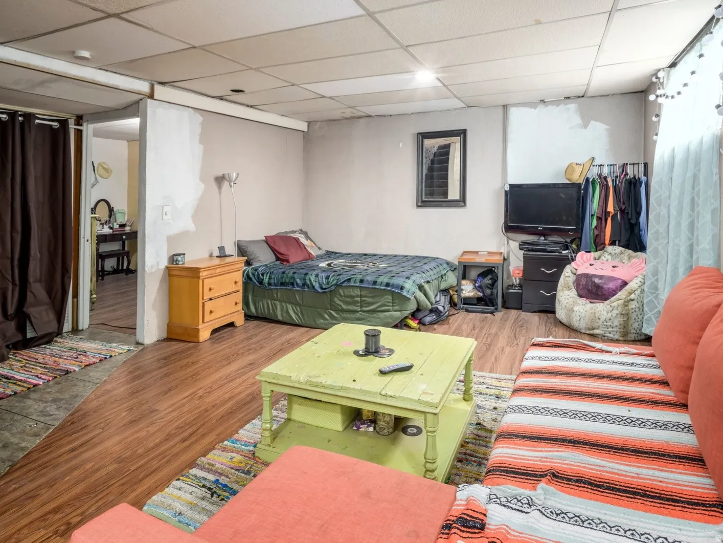 Versatile lower level space featuring wood-finish flooring, a drop ceiling, and distinct areas for various uses