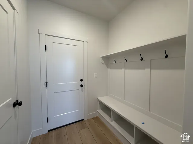 Built-in storage bench with open shelving, wall-mounted coat hooks, and crisp white paneling