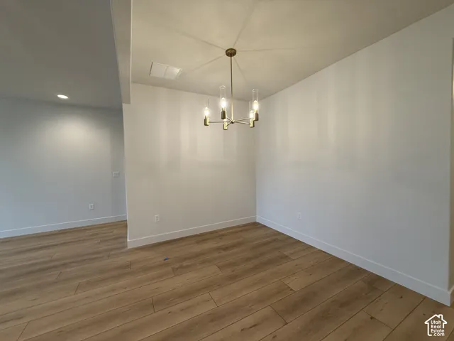 Wood-finish flooring throughout, modern brass chandelier, recessed ceiling lighting, and crisp white walls